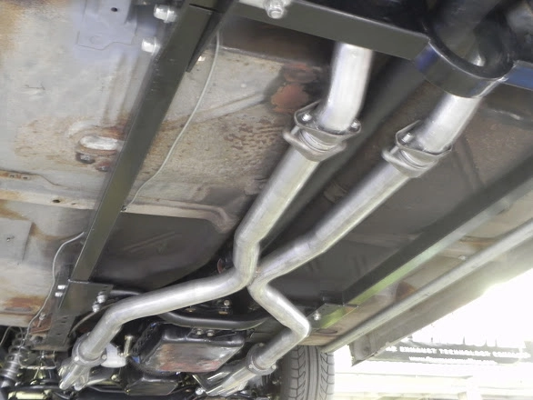 Angled view of dual exhaust pipes running along the bottom chassis of a vehicle