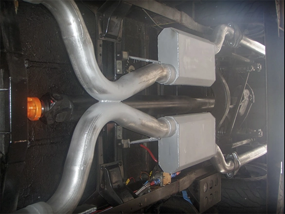 Underside view showing dual polished mufflers and twin exhaust pipes