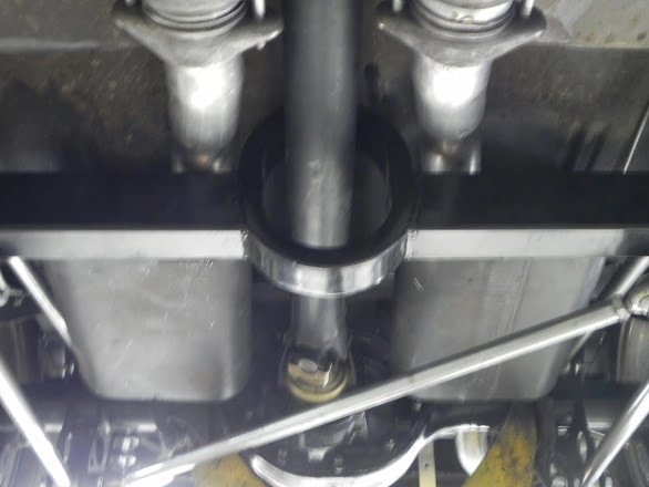 Close-up of an exhaust pipe clamp and hanger component under a car