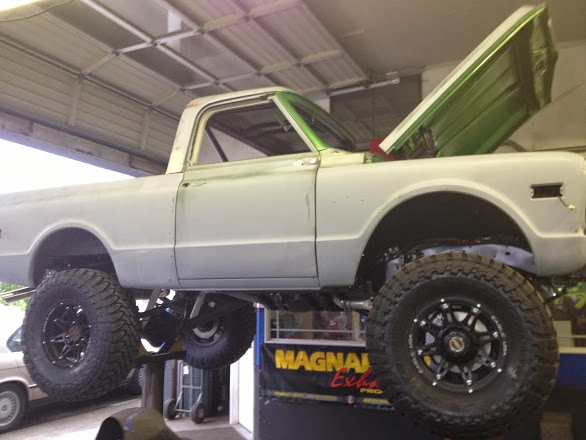 Side profile of a lifted vintage white Chevrolet truck on a shop lift