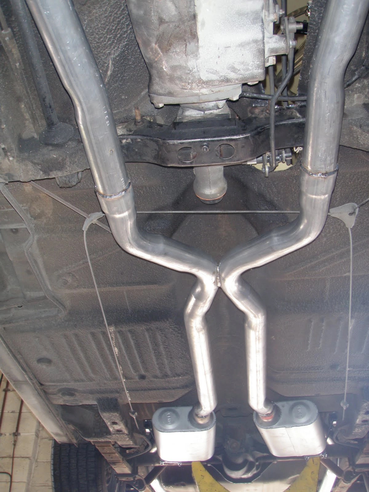 Underside shot looking down a long, custom-fitted dual X-pipe exhaust system
