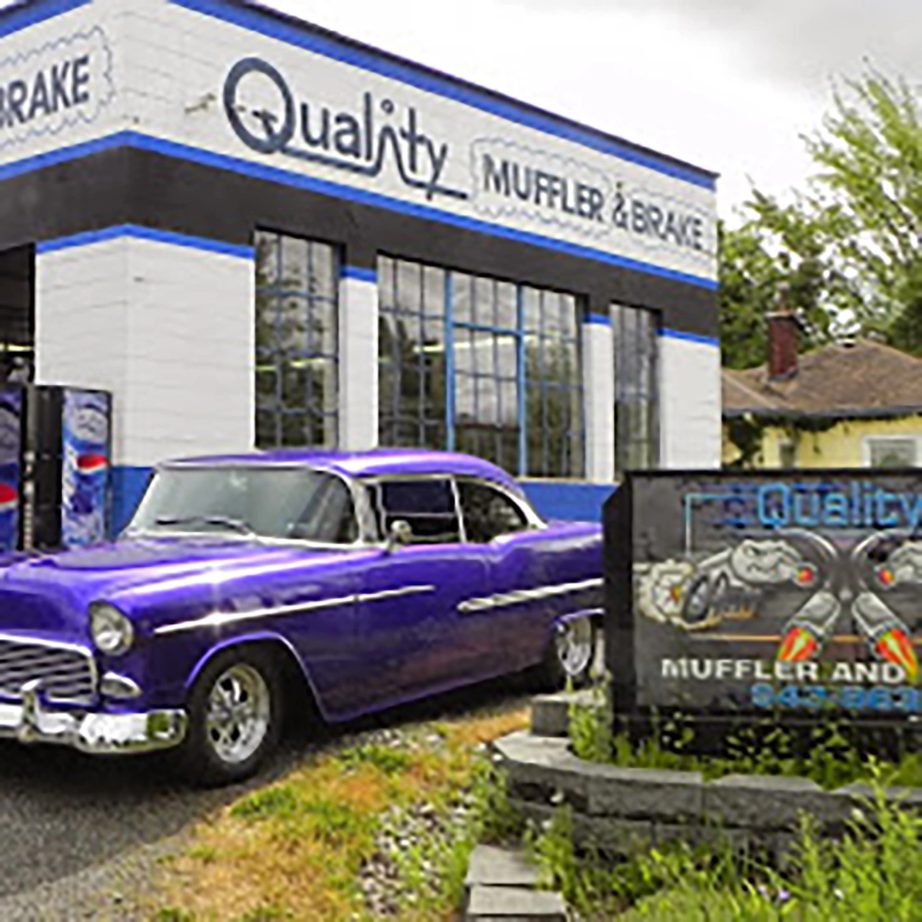 Vintage purple classic car parked outside Quality Muffler and Brake shop