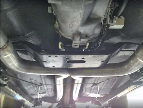 View from beneath a car showing the transmission and straight exhaust pipes