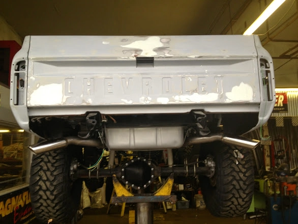 Rear view undercarriage of a white Chevrolet truck showing new dual exhaust system
