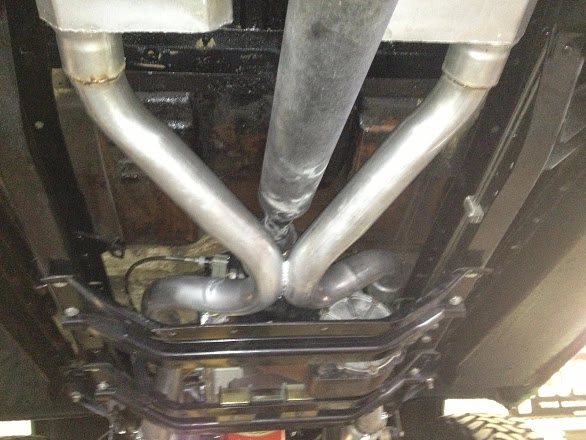 Close-up of a custom stainless steel X-pipe exhaust system installed under a vehicle